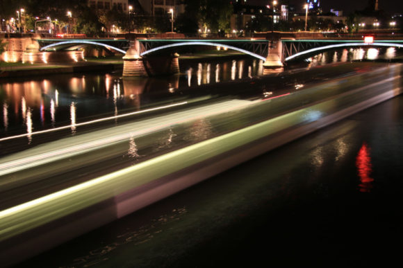 Ein Flusskreuzfahrtschiff verlässt das nächtliche Frankfurt und setzt seine Reise mainaufwärts fort.